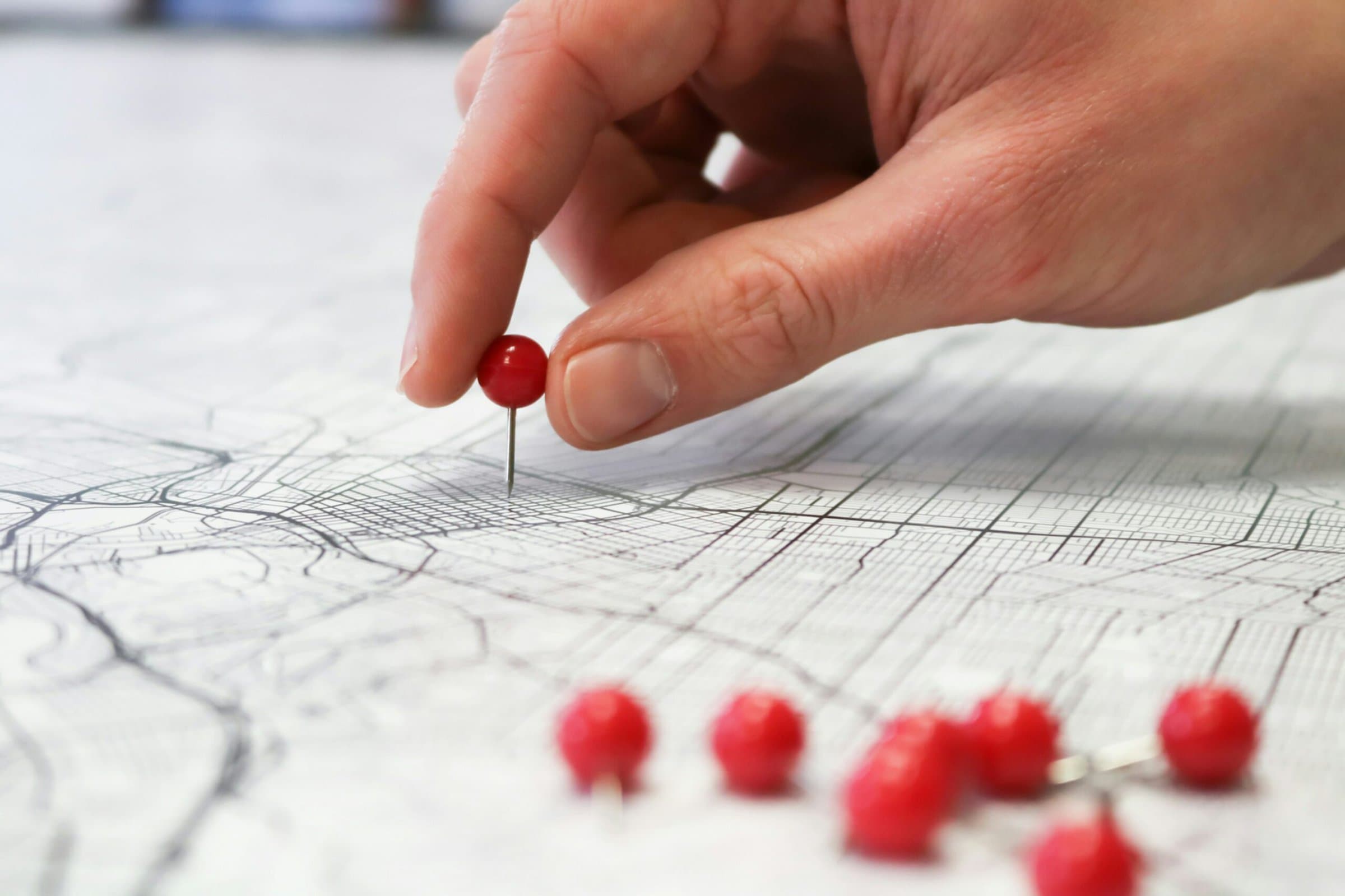 Map with pushpin Hand placing pushpin on a map