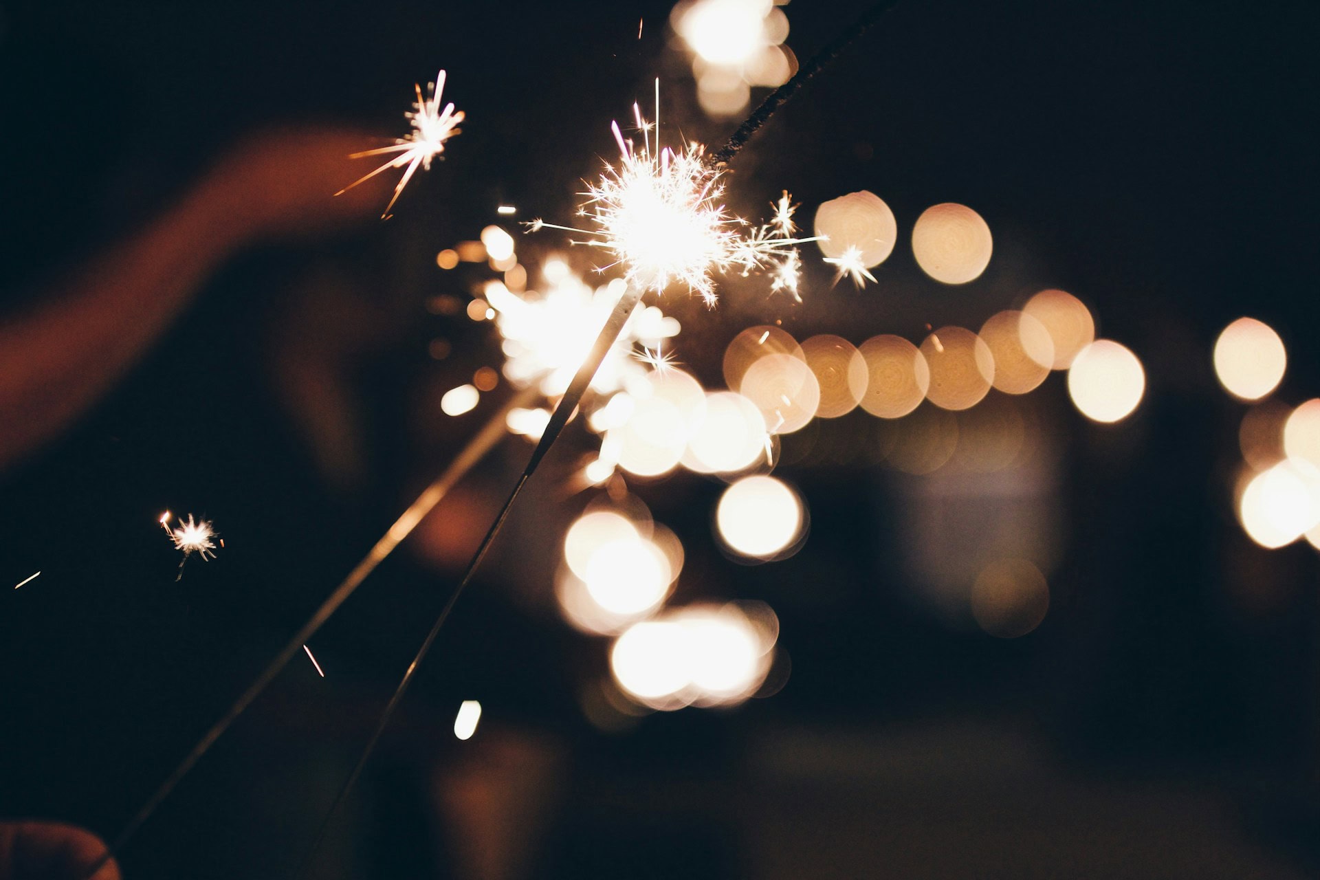 An individual holding a sparkler, illuminating the darkness with a shimmering light.