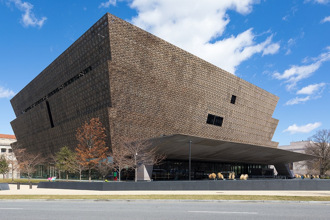 The outside of the building of the National Museum of African American History and Culture against a blue sky with clouds